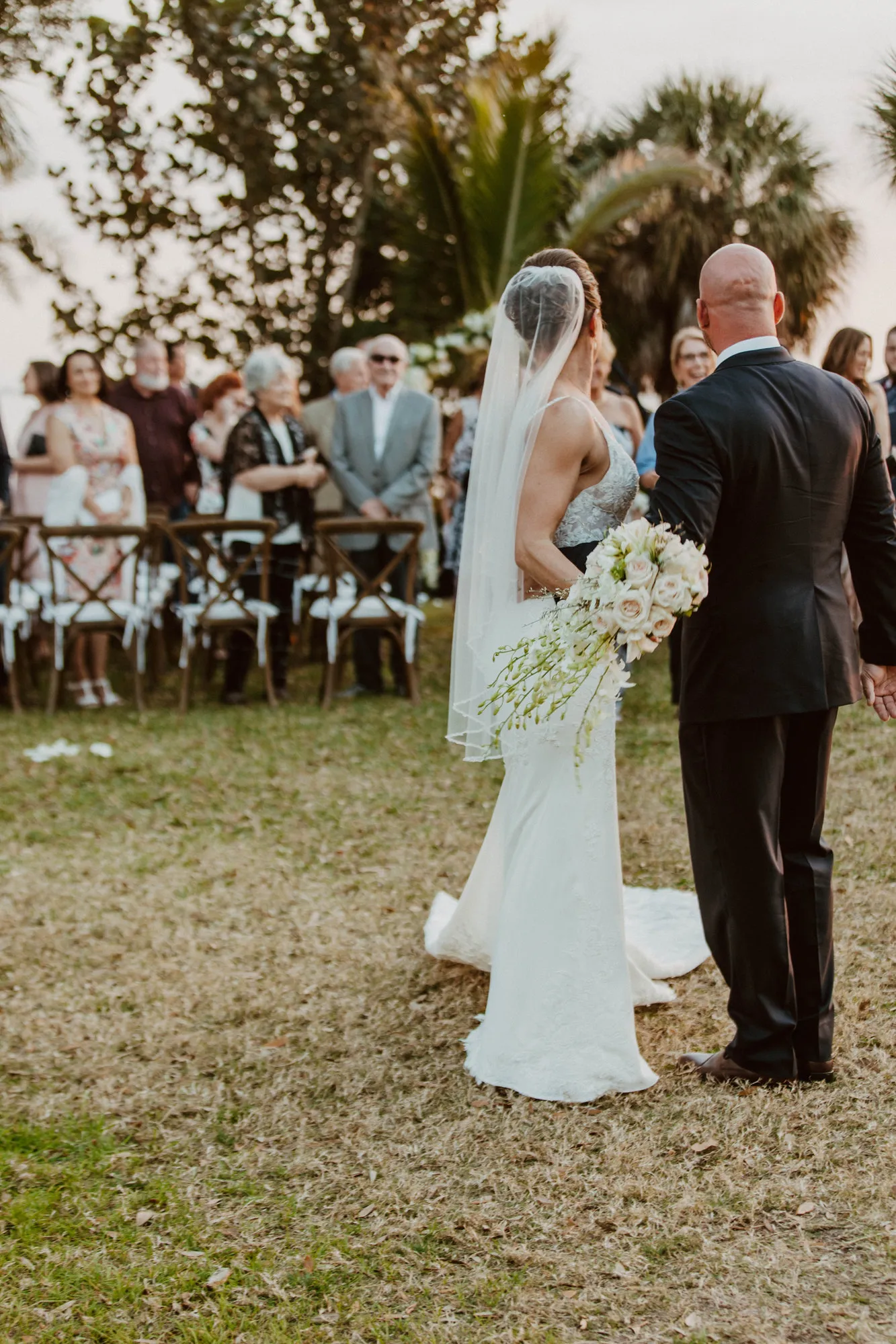 Bride and groom standing together on the lawn as guests look on