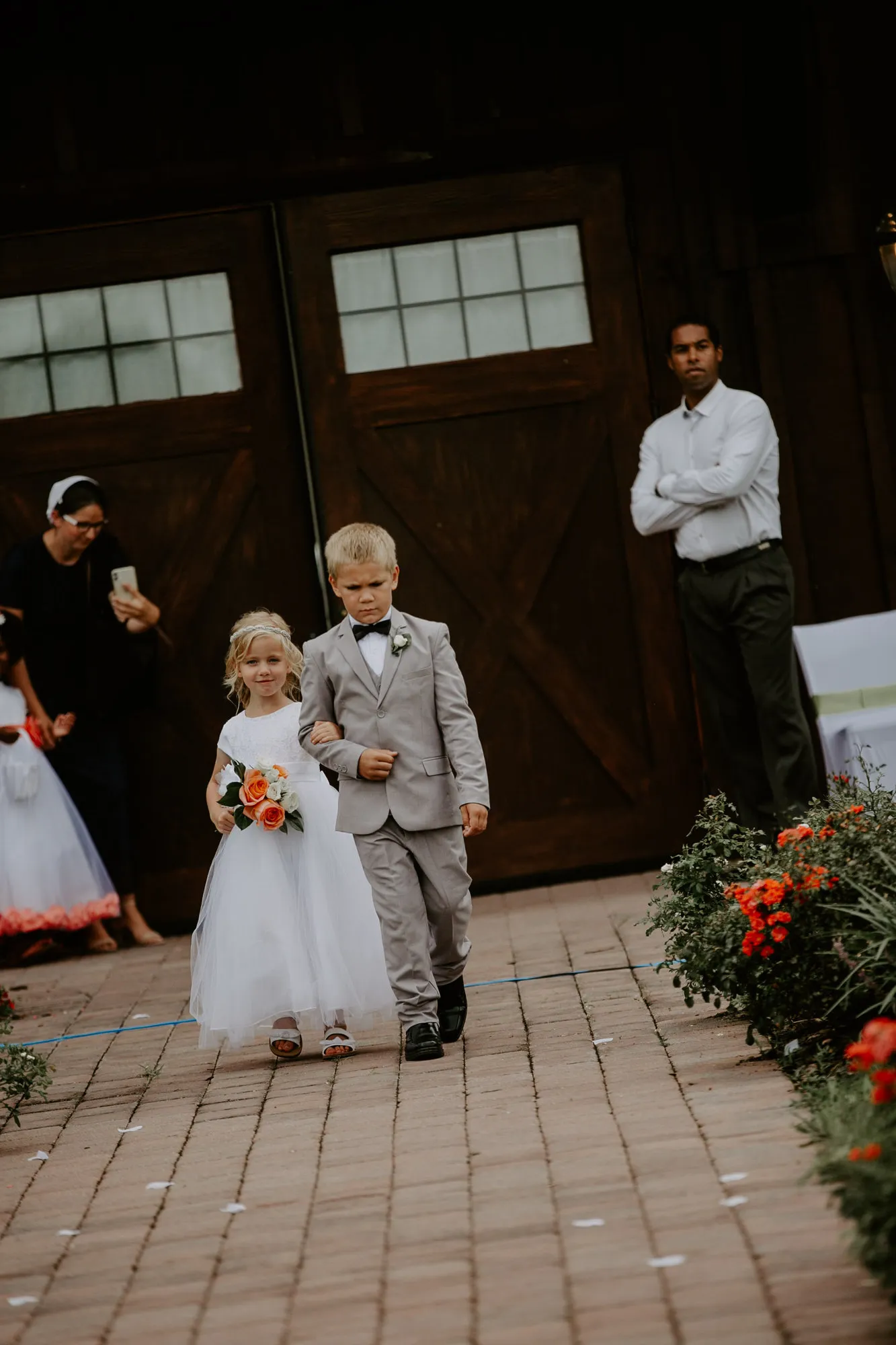 Flower girl and ring bearer walking down the brick aisle arm in arm