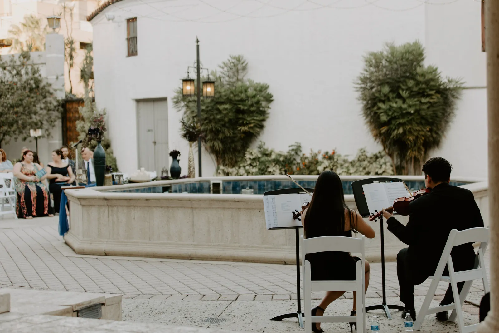 String duo playing beside the courtyard fountain before the ceremony