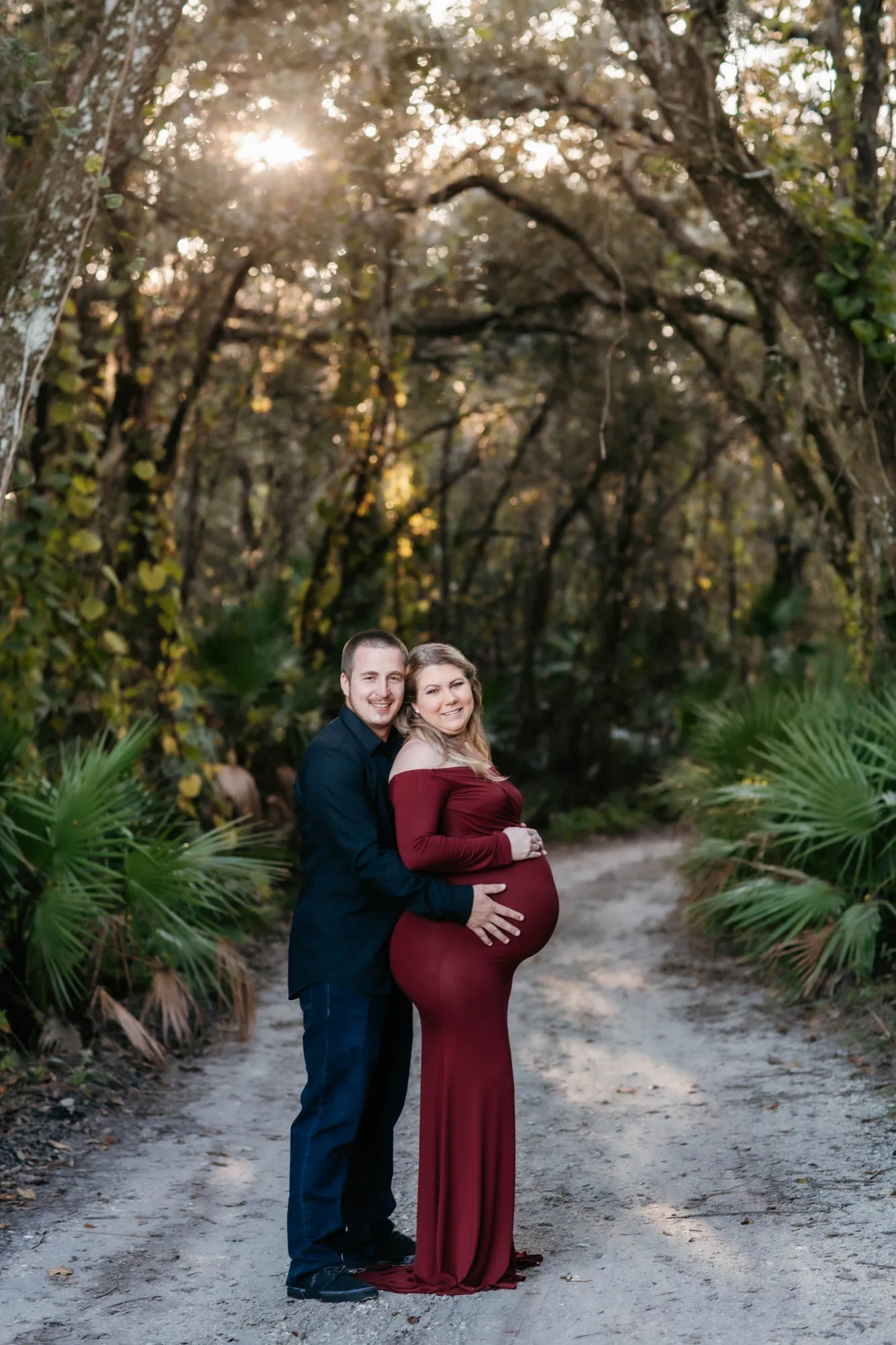 Couple standing on a sandy track under a tunnel of trees