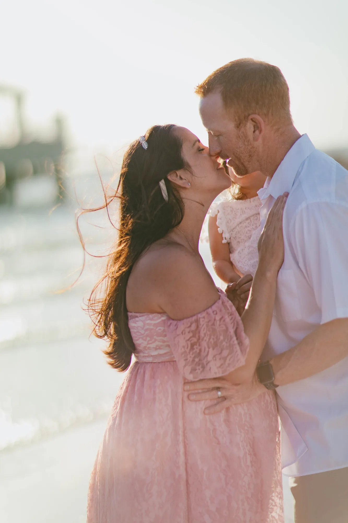Parents kissing with their toddler held between them
