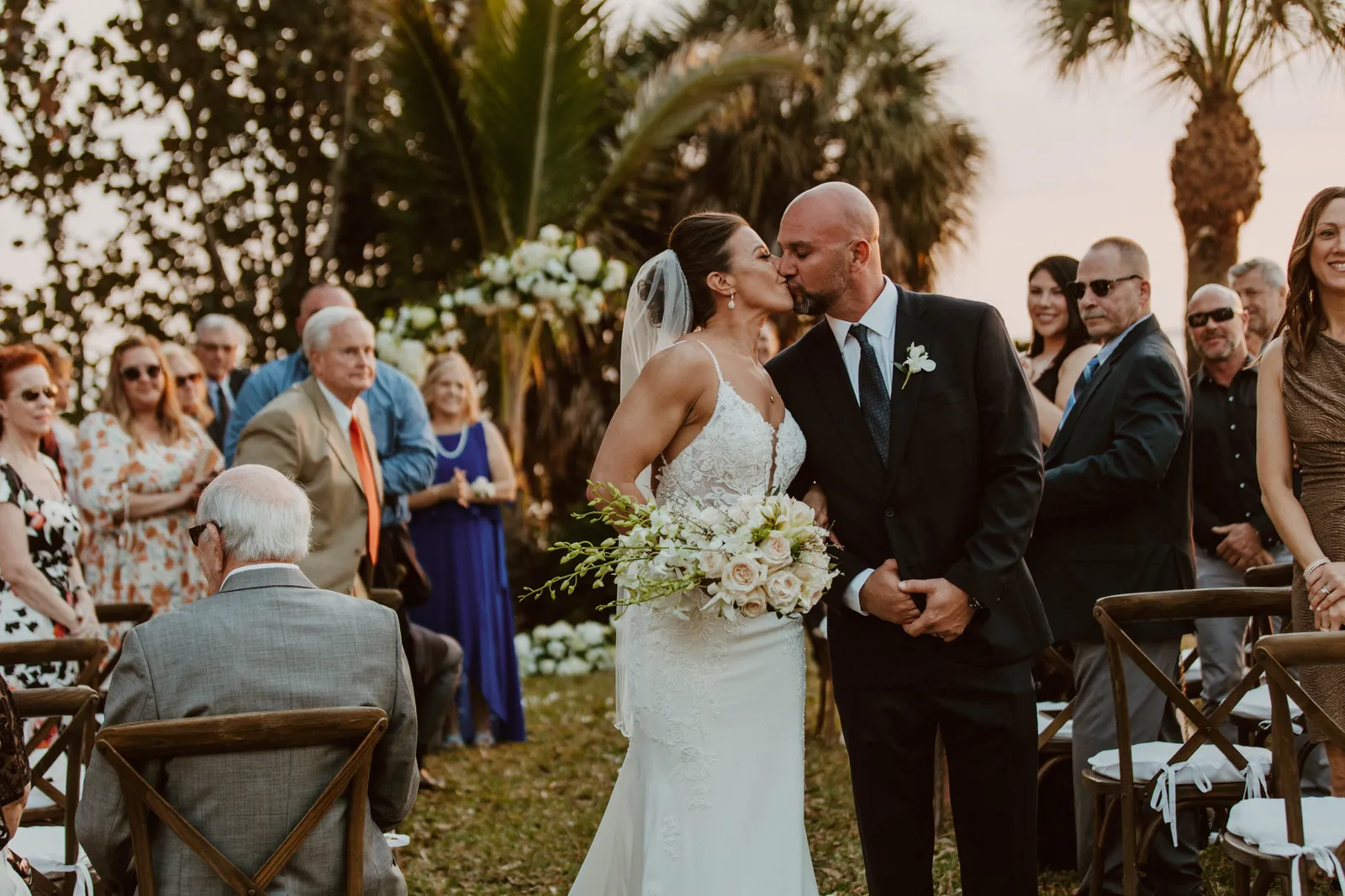 Bride and groom kissing in the aisle, surrounded by their guests
