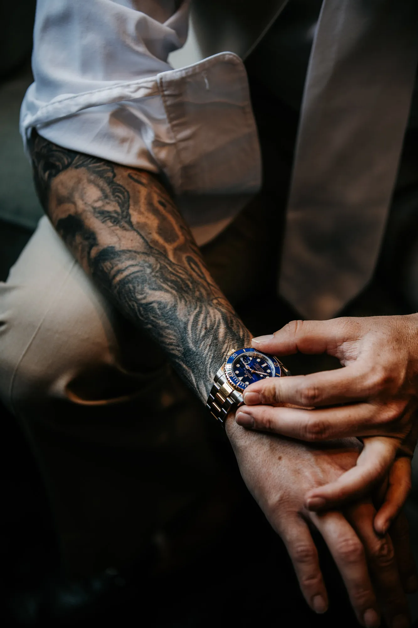 Groom adjusting his watch on a tattooed forearm