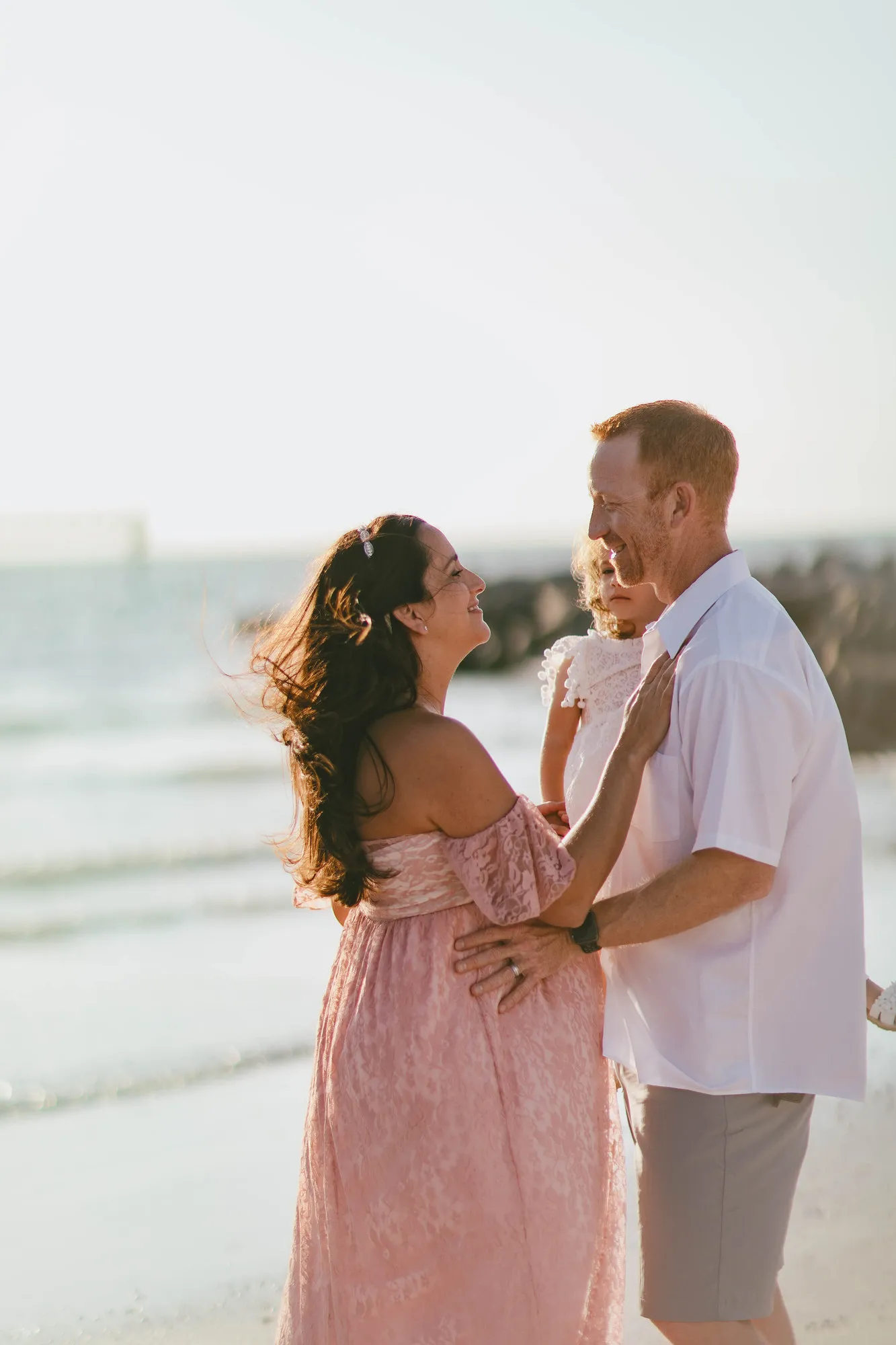 Mother leaning in to her husband and daughter by the water