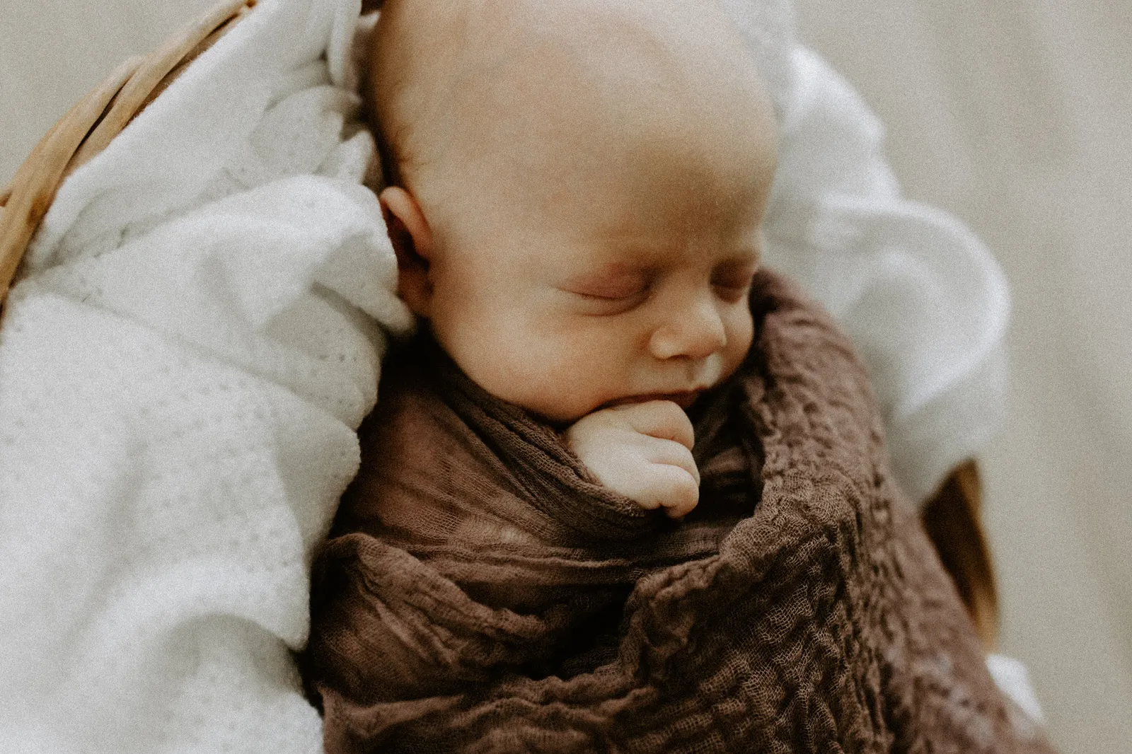 Newborn asleep, wrapped in a brown blanket