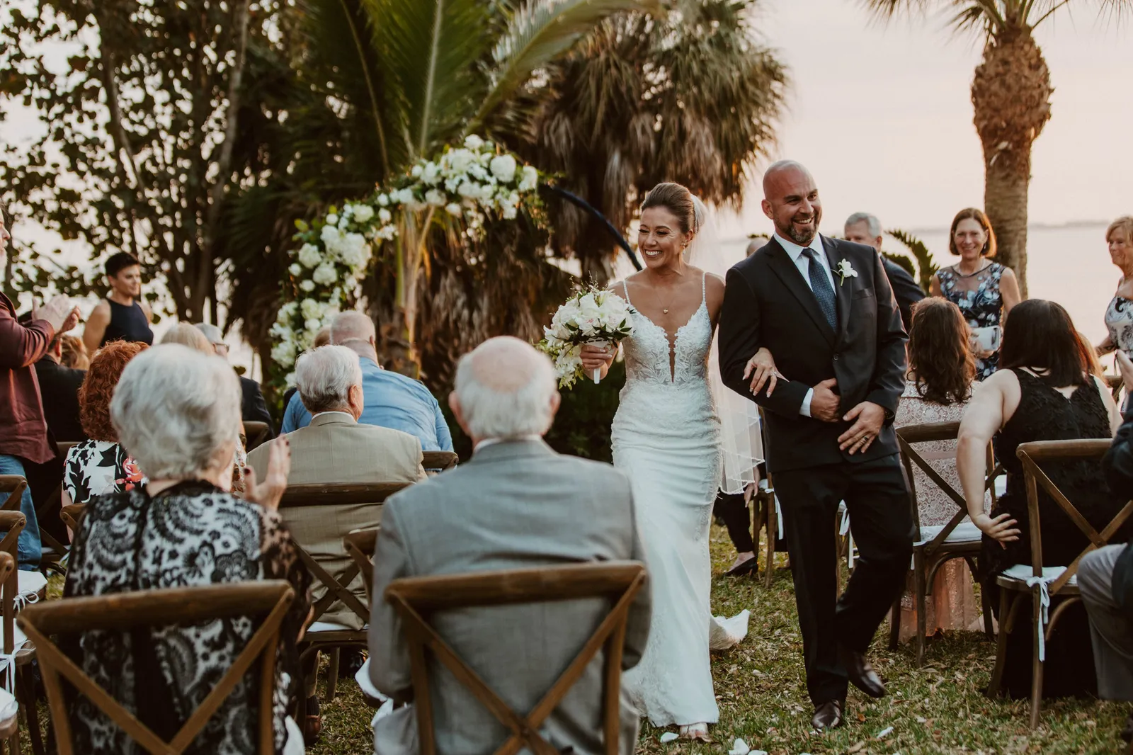 Newlyweds walking up the aisle between rows of seated guests