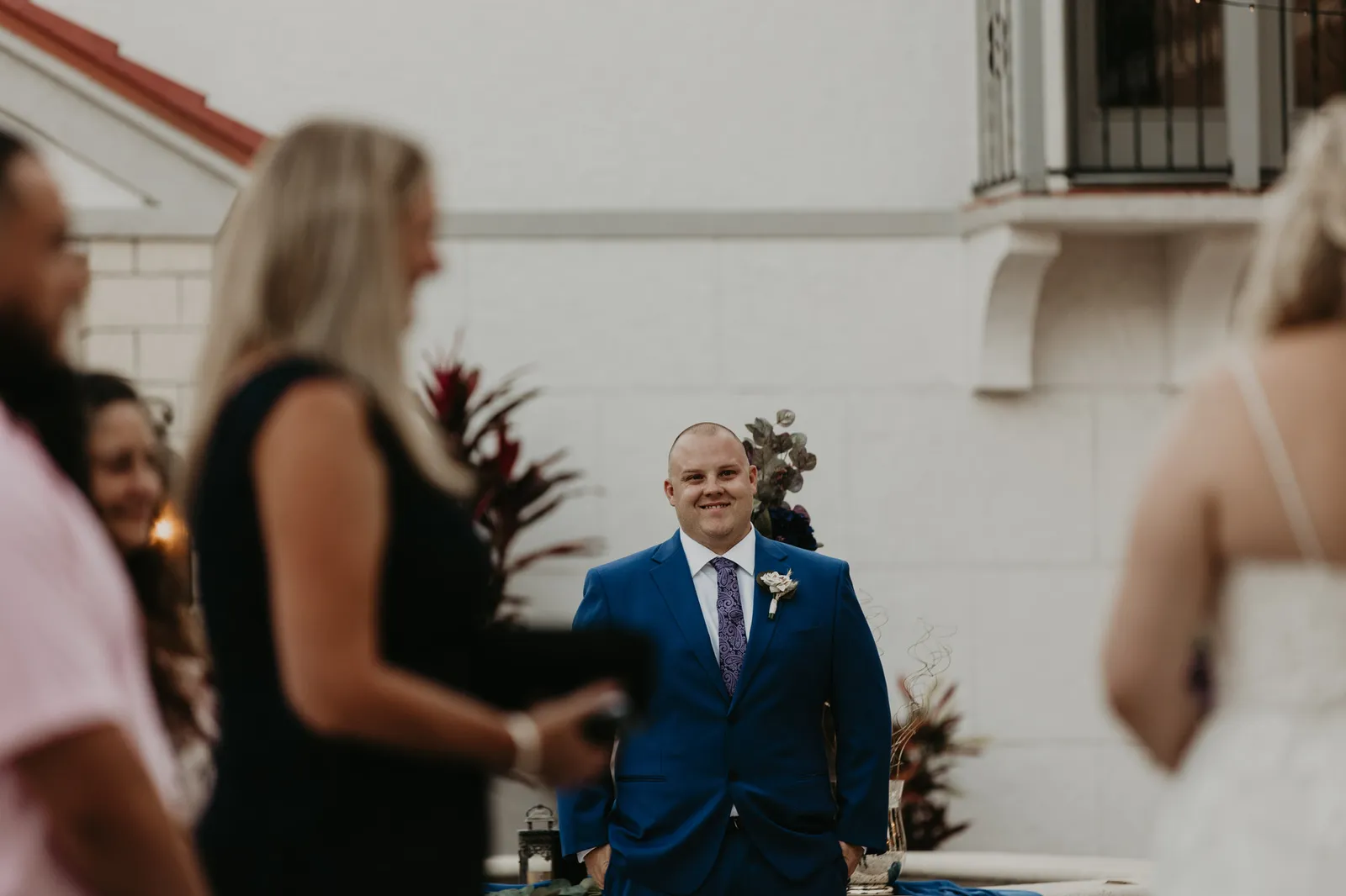 Groom in a blue suit smiling as he sees his bride arrive