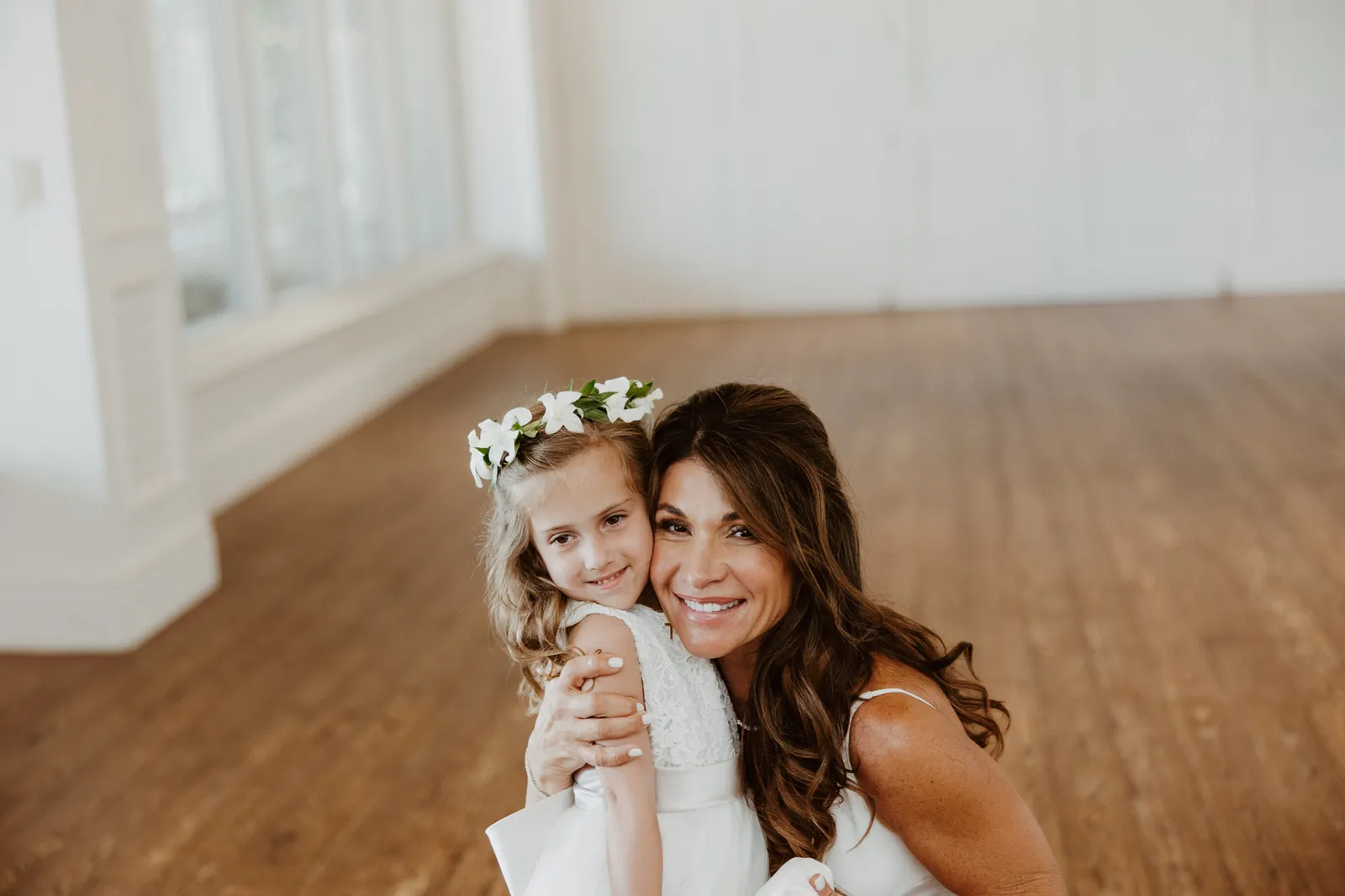 Flower girl in a floral crown cheek to cheek with the bride