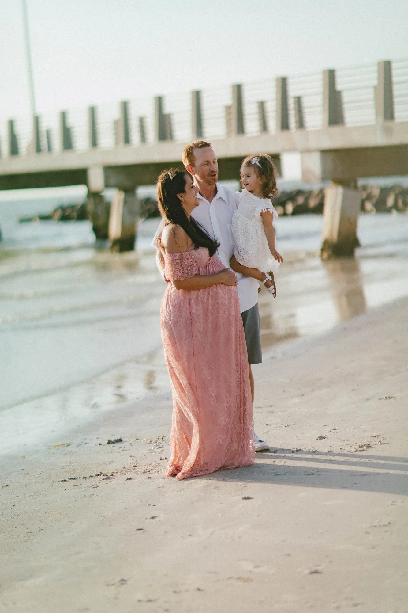 Family standing on the wet sand with the pier behind them