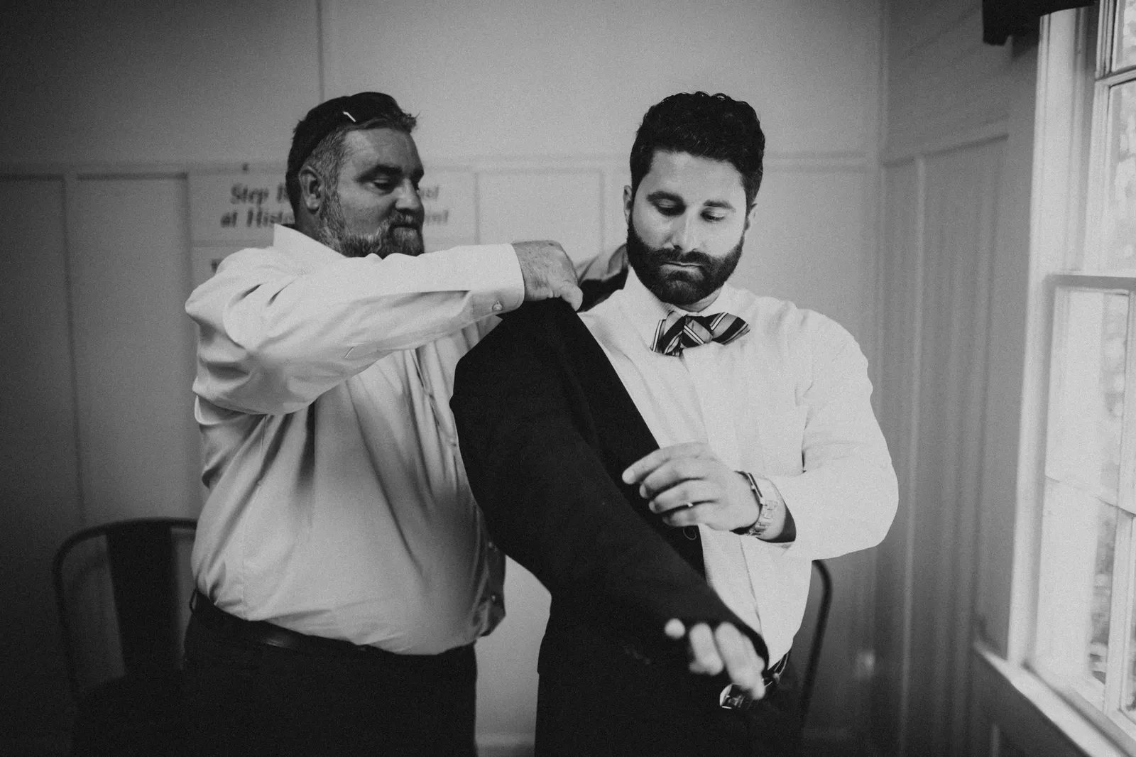 Man helping the groom into his jacket, in black and white