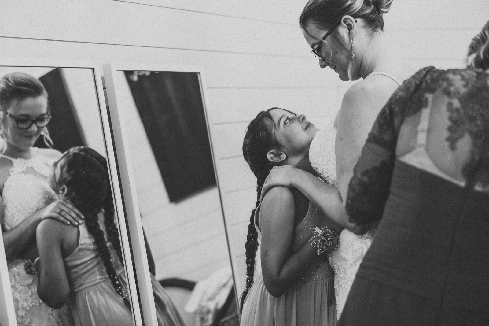 Girl looking up at the bride as she is dressed, in black and white