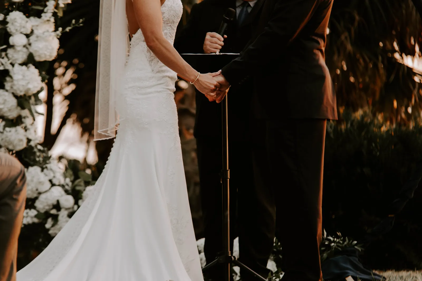 Bride and groom holding hands at the altar, seen from behind