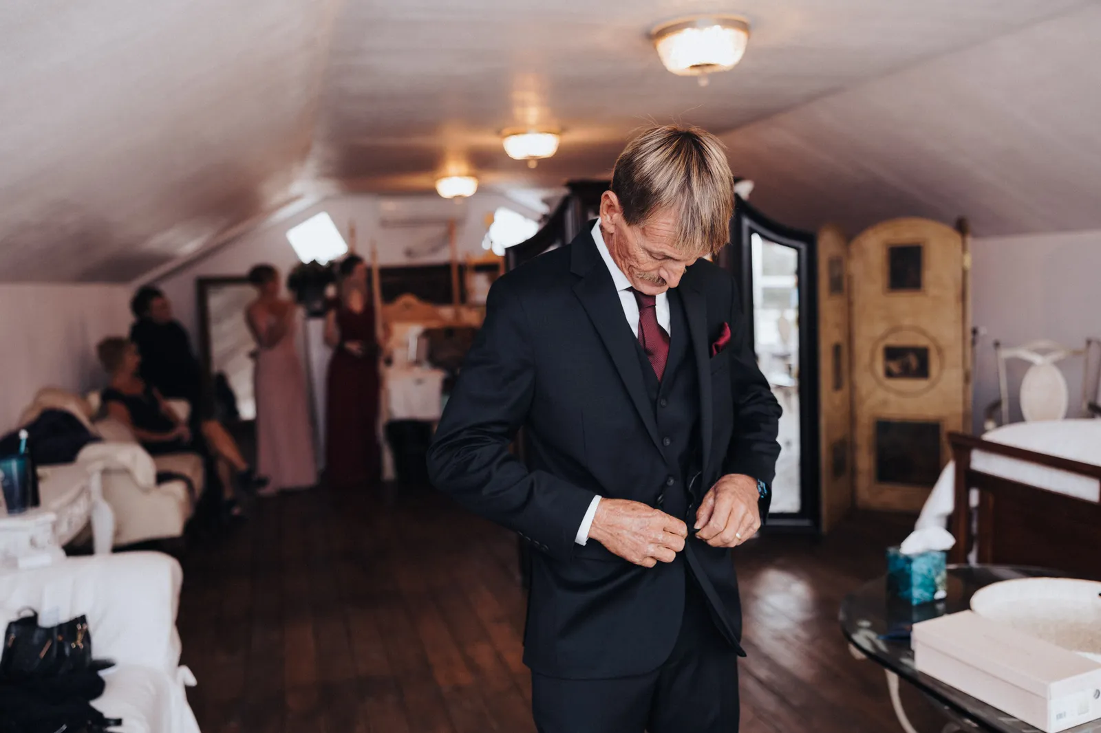 Man in a dark suit buttoning his jacket in the dressing room
