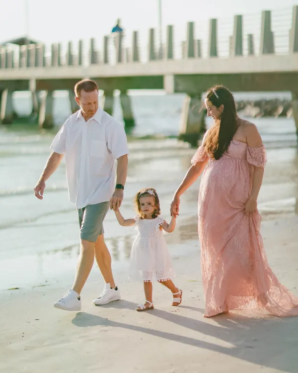 Parents walking along the beach with their toddler daughter at Fort De Soto