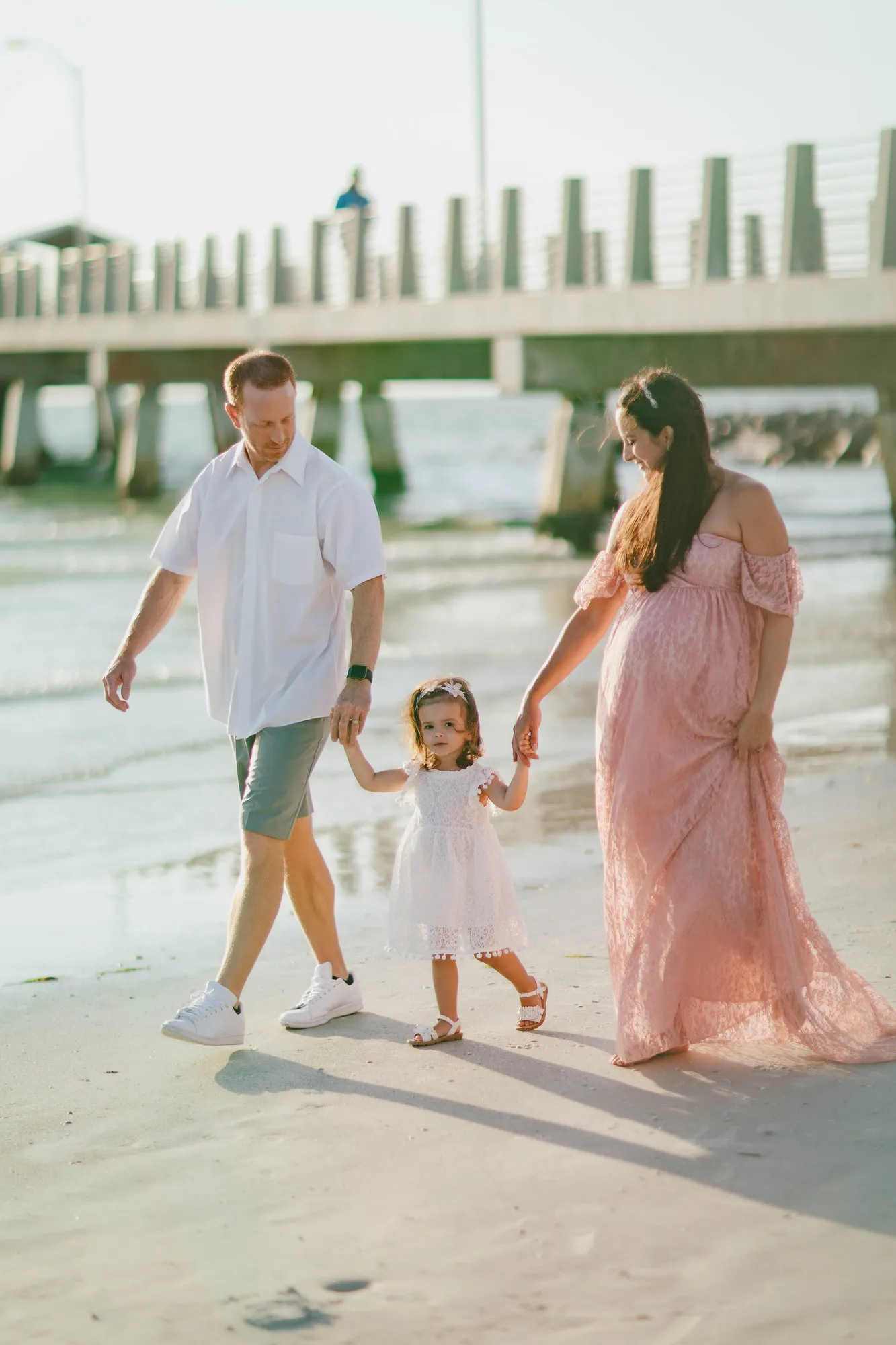 Parents walking along the beach with their toddler daughter at Fort De Soto