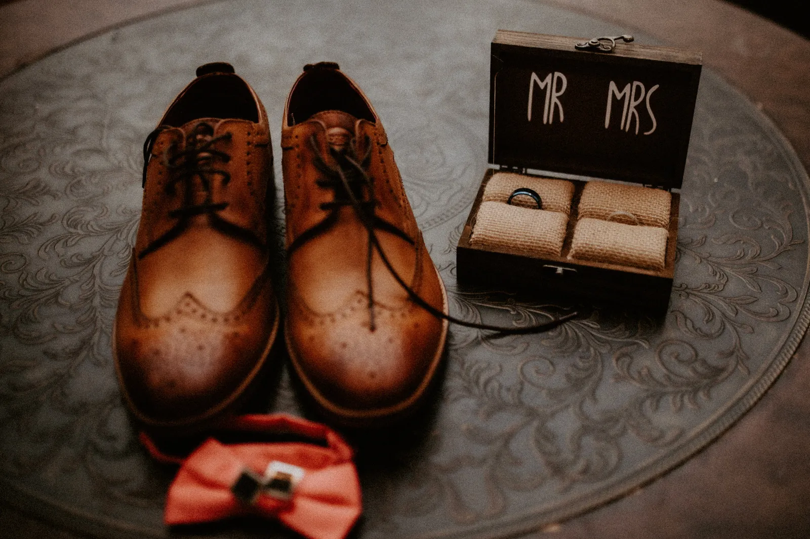 Brown brogues beside a Mr and Mrs ring box and a coral bow tie