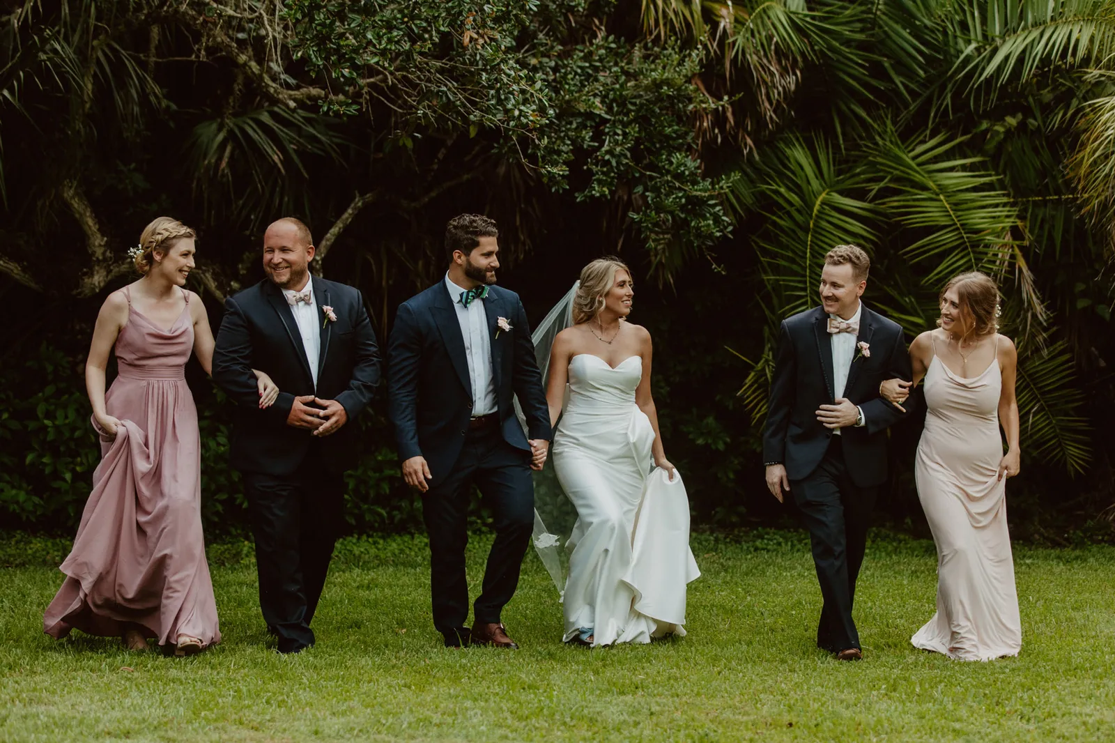 Bride and groom walking across the lawn with their wedding party
