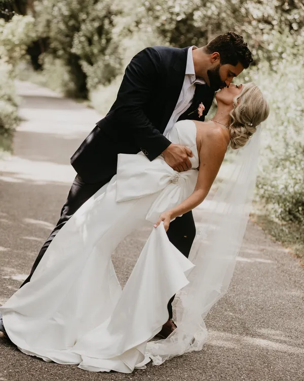 Groom dipping his bride for a kiss on a garden path