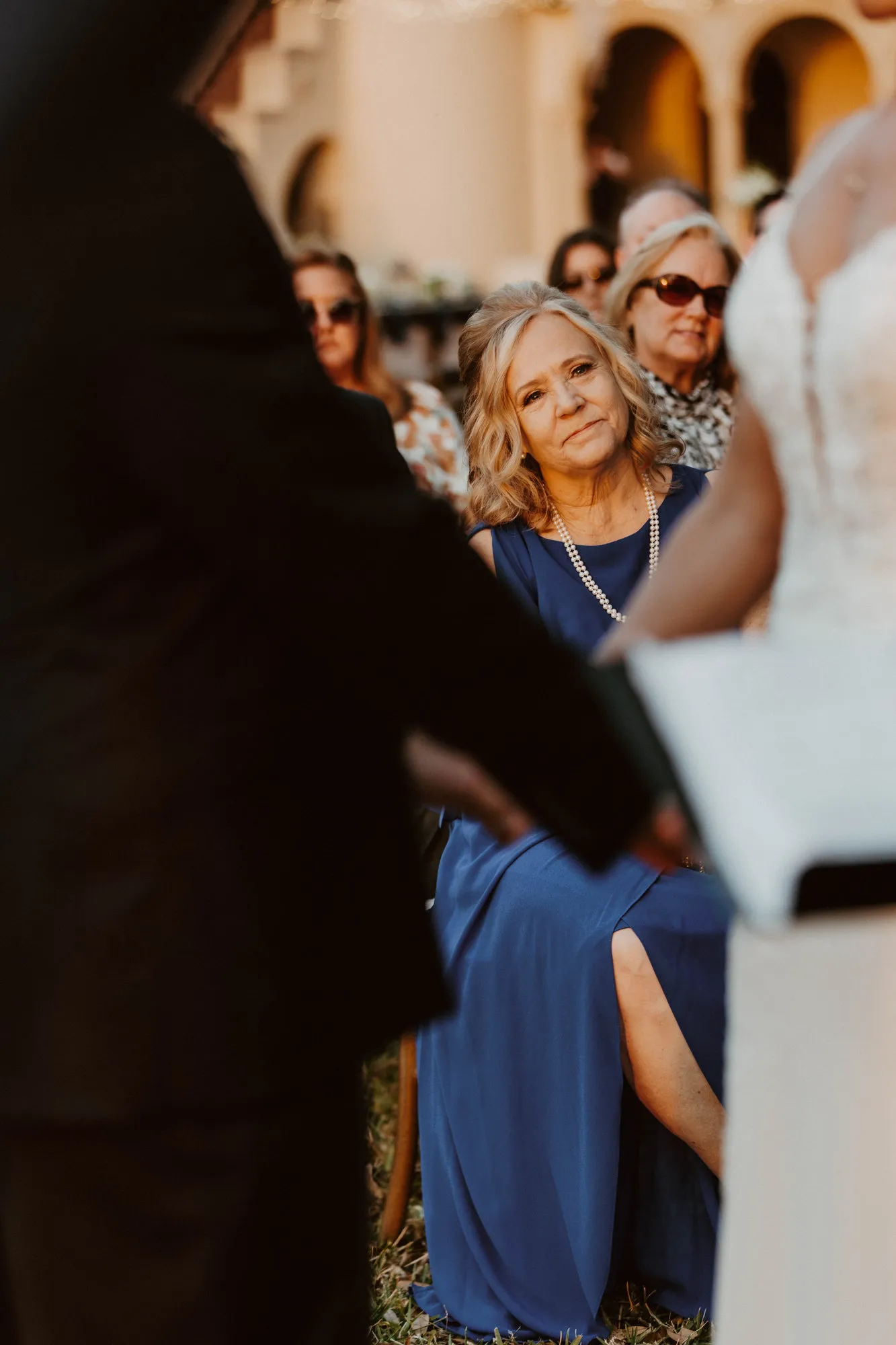 Guest in a blue dress watching the ceremony from her seat