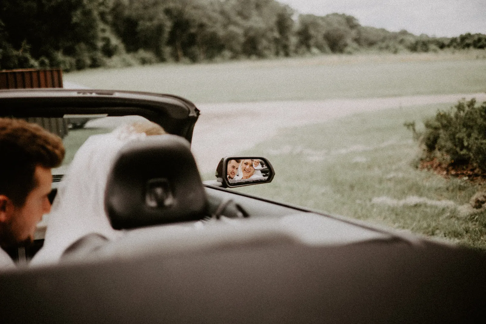 The couple reflected in the wing mirror of the convertible