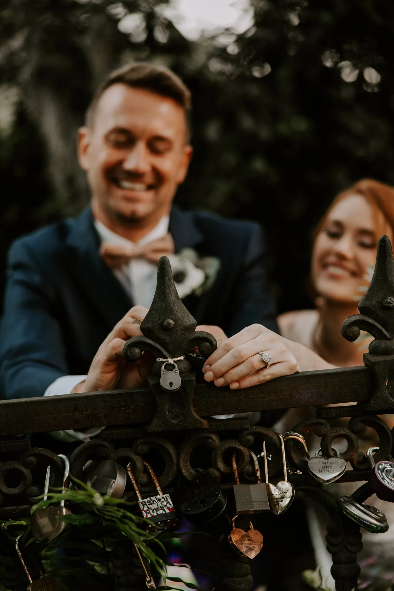 Bride and groom laughing as they fasten a padlock to the iron gate