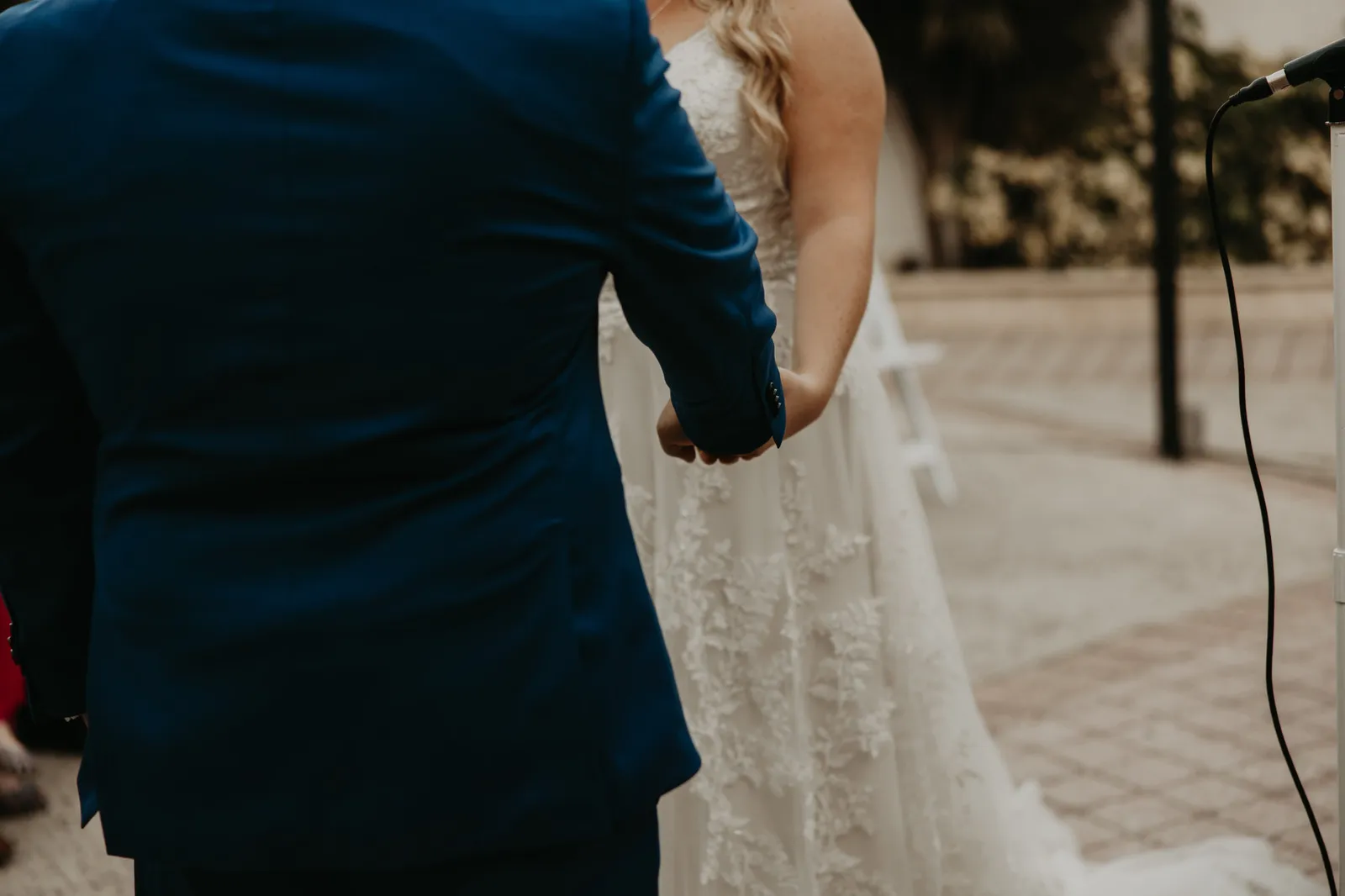 Bride and groom holding hands during the ceremony, close up