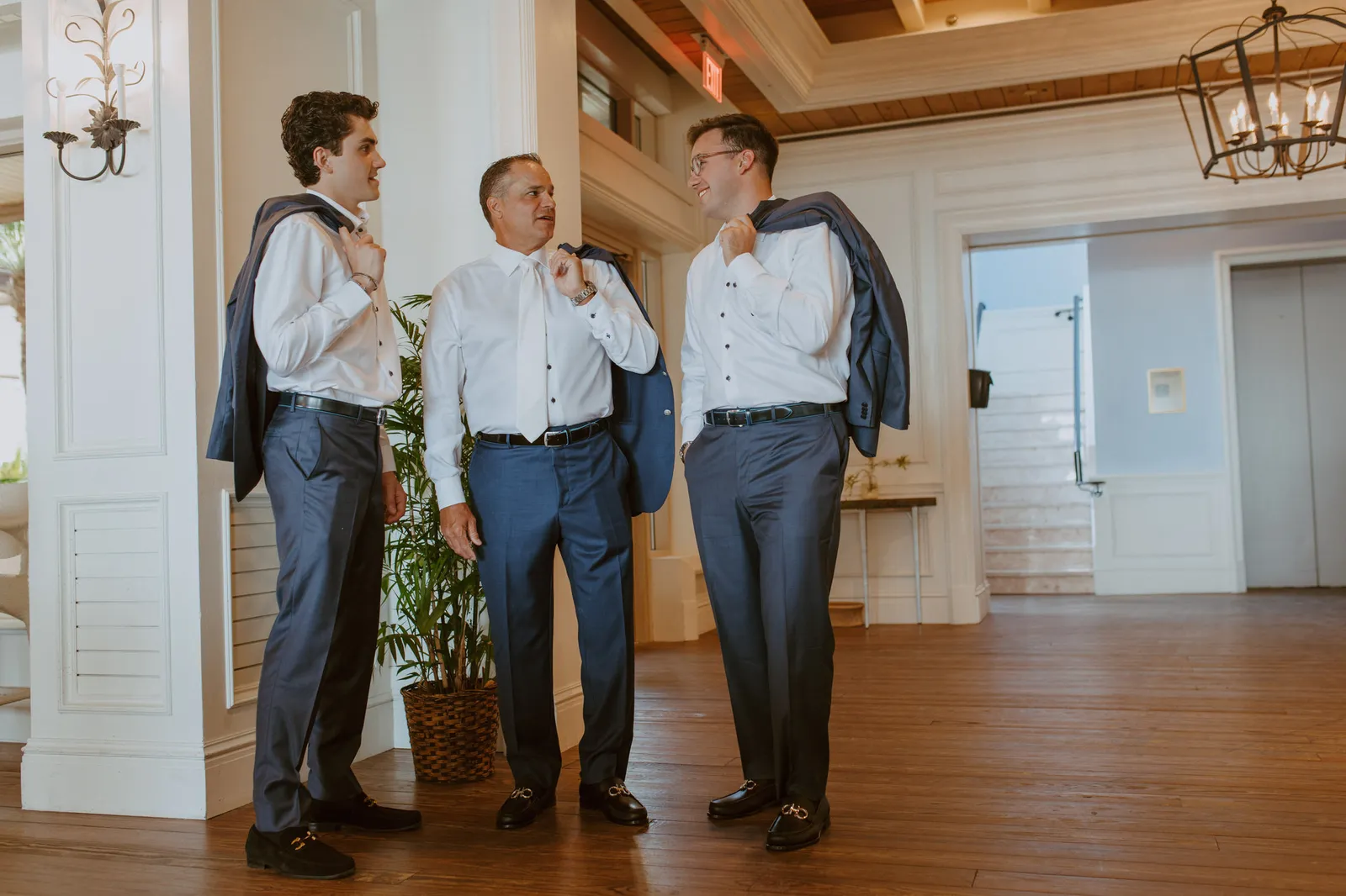 Three men in white shirts with their jackets slung over their shoulders