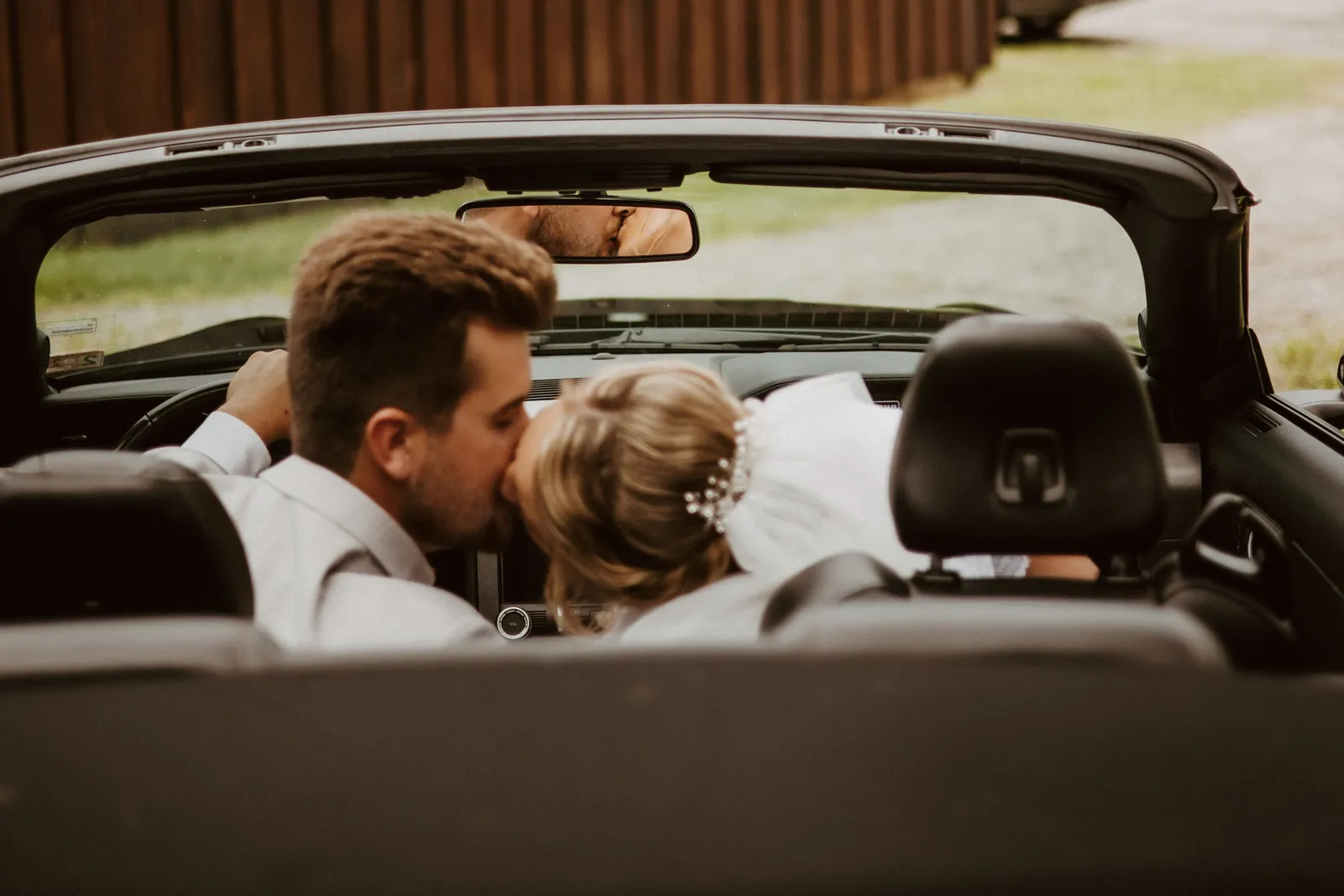Newlyweds kissing in a convertible