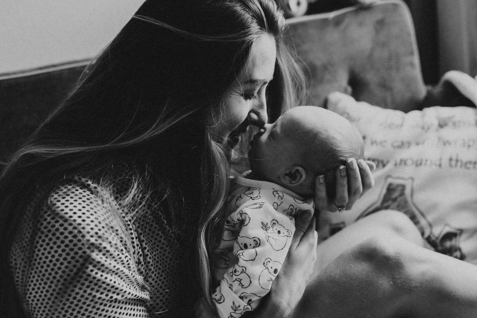 Mother kissing her newborn's forehead, in black and white