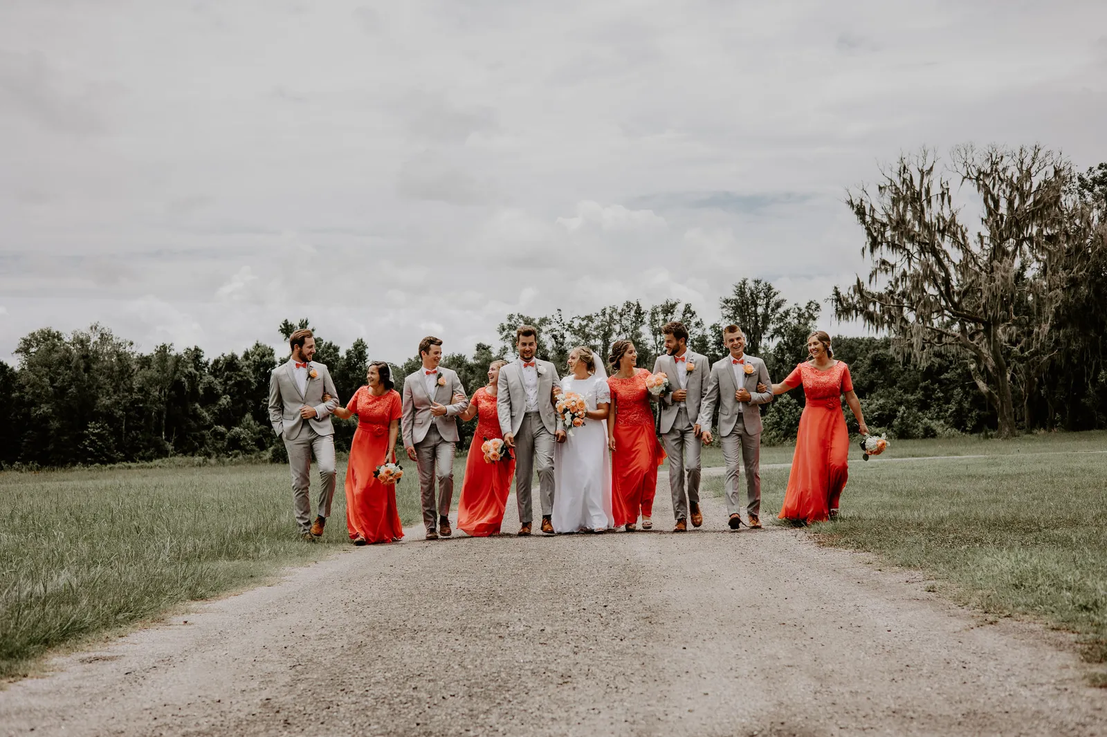 Wedding party walking down a gravel road toward the camera