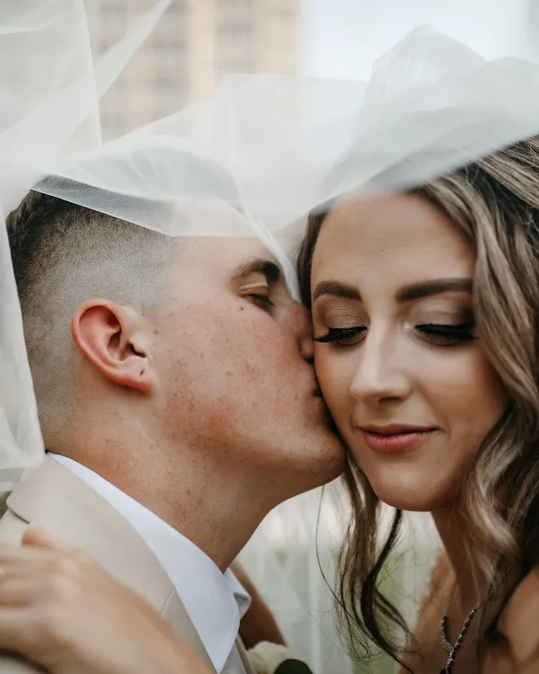 Groom kissing his bride's cheek beneath her veil at their Ritz-Carlton, Sarasota wedding