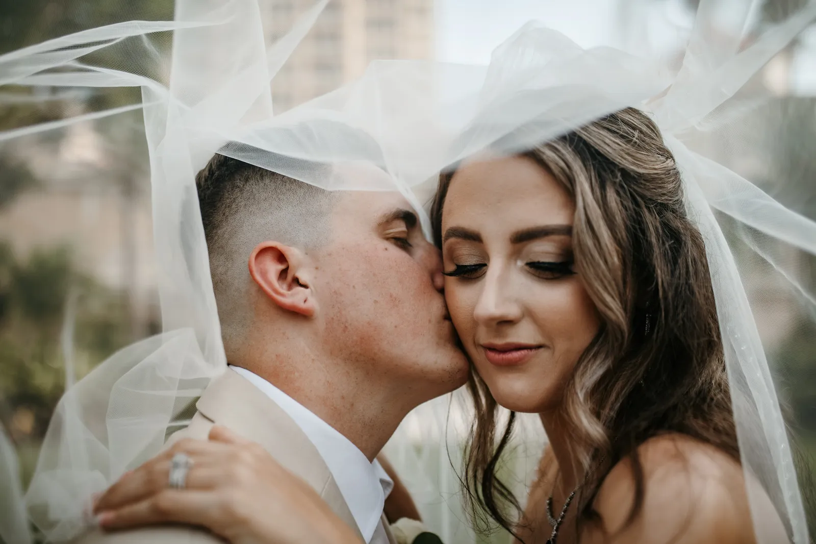 Groom kissing his bride's cheek beneath her veil at their Ritz-Carlton, Sarasota wedding