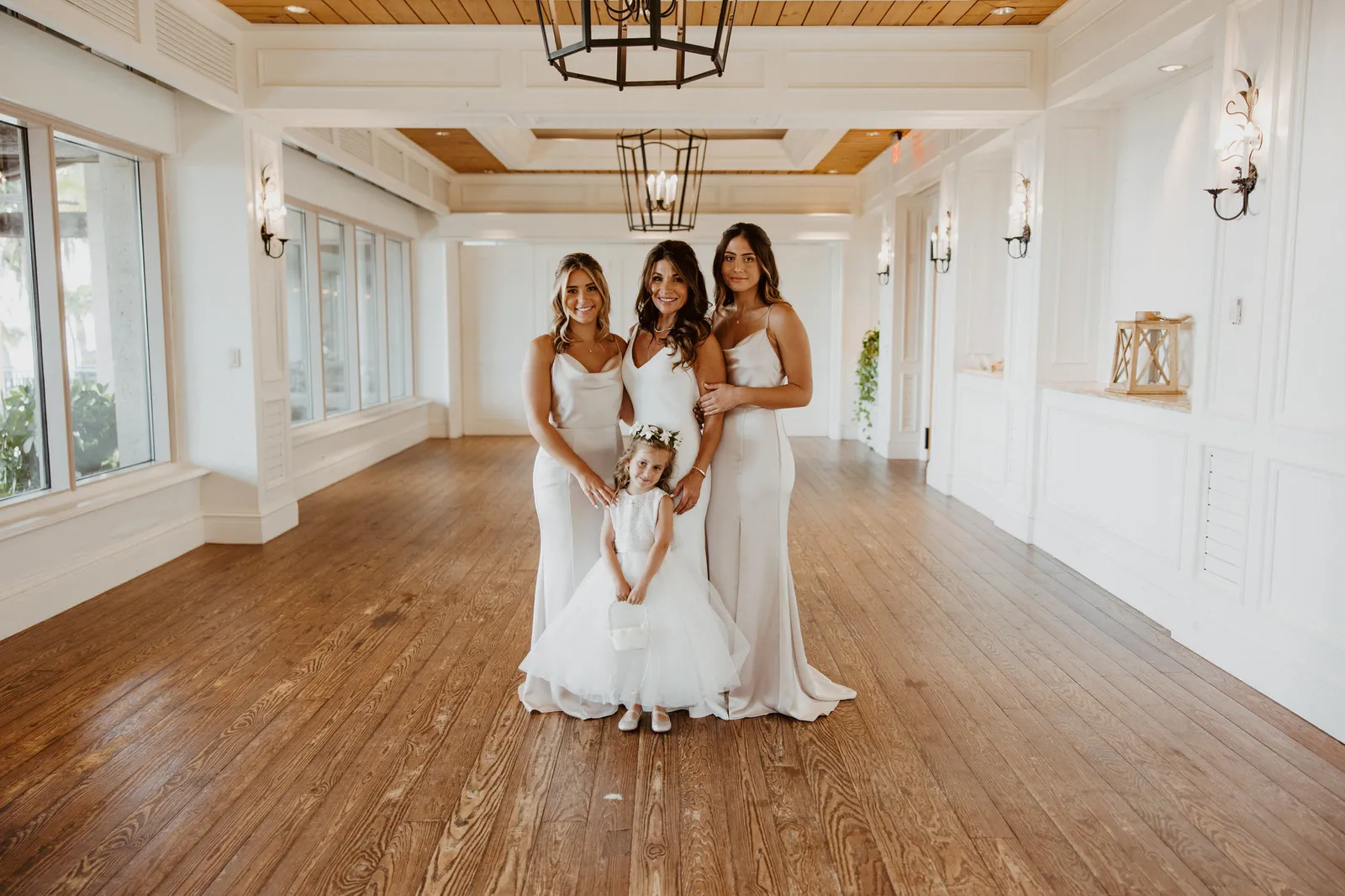Bride with two bridesmaids and the flower girl in a white room
