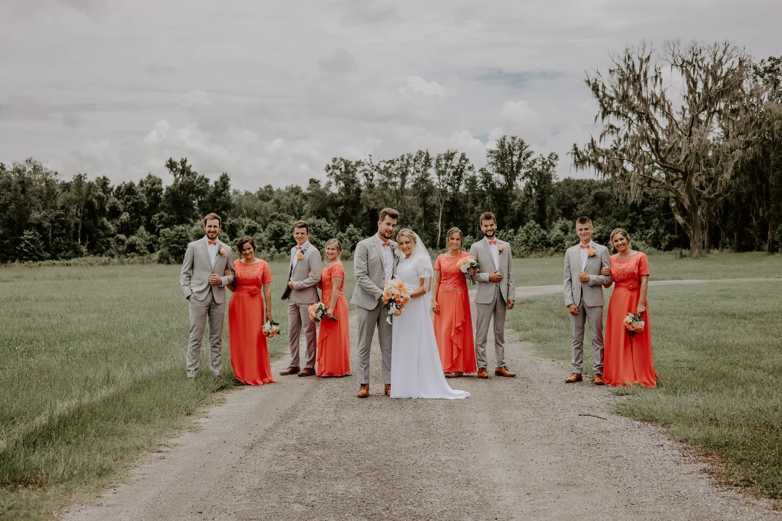 Wedding party lined up on a gravel road, the couple in the middle