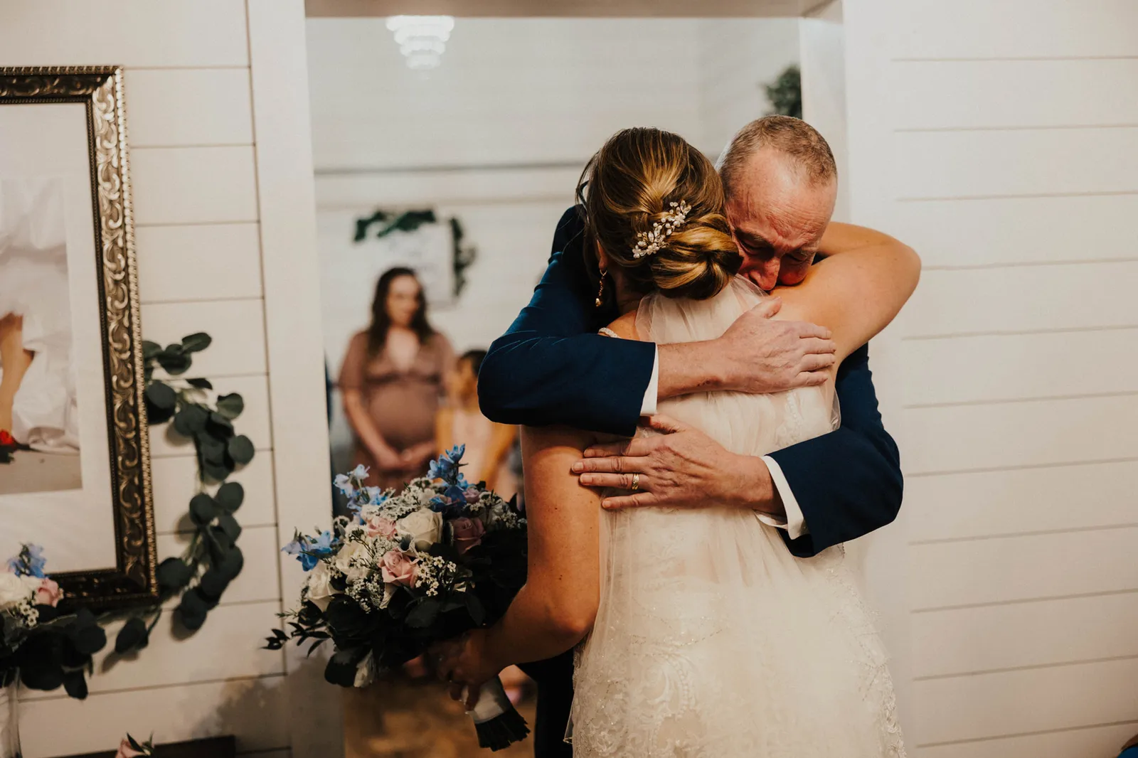 Man in a suit hugging the bride tightly