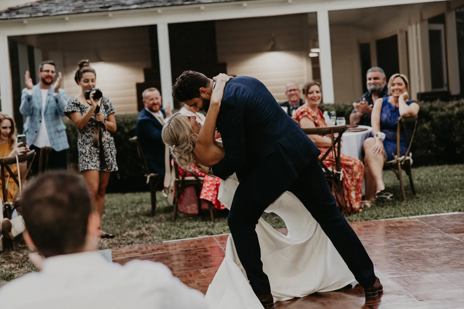 Groom dipping the bride on the dance floor as guests cheer