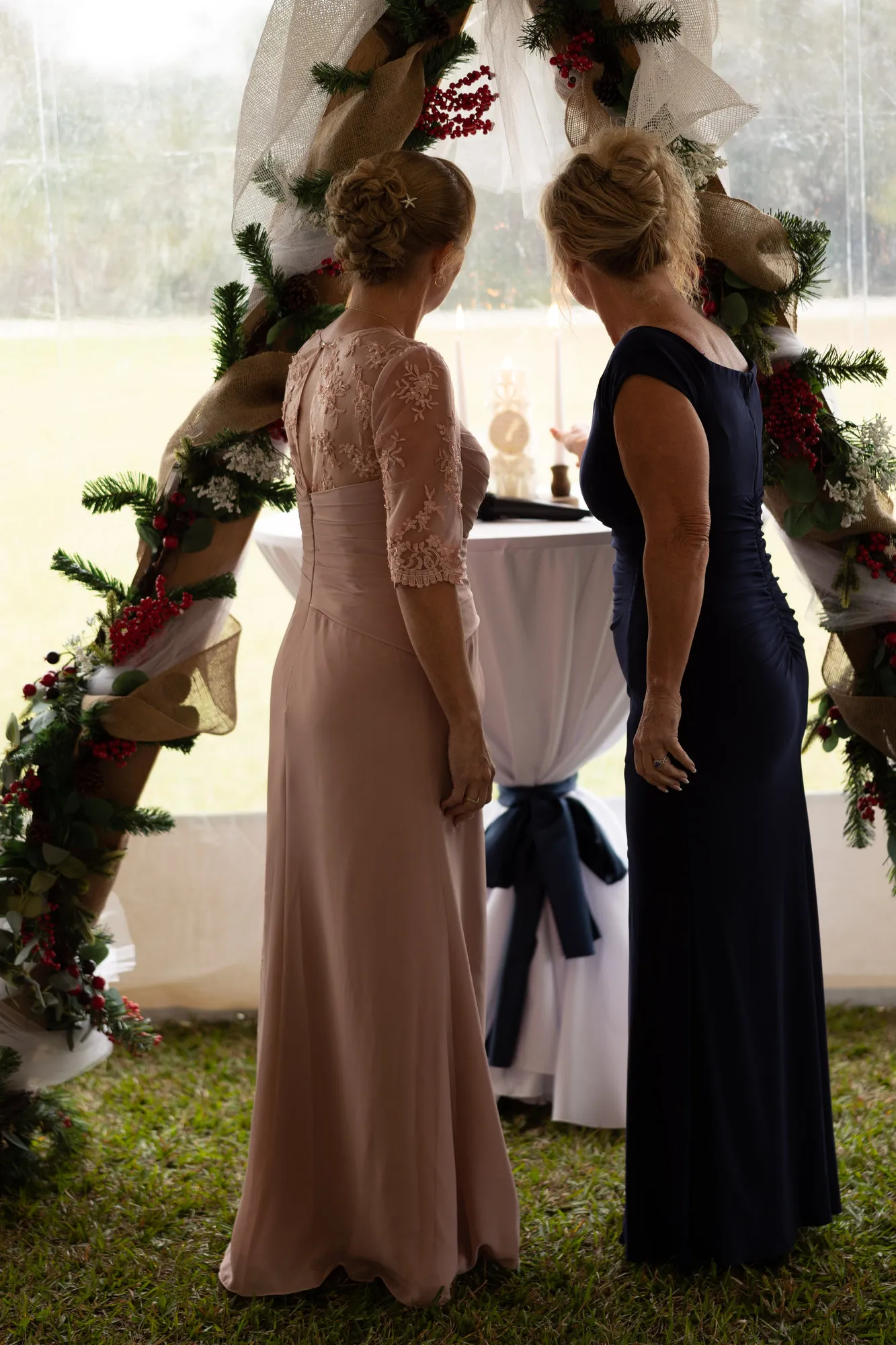 Two women under the arch turning toward each other, a field beyond