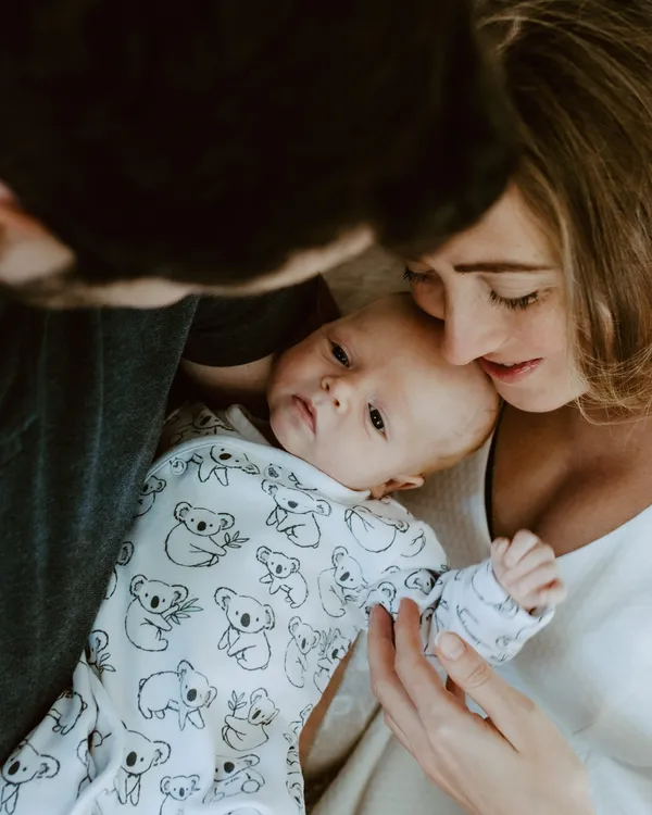 New parents kissing over their newborn son at home