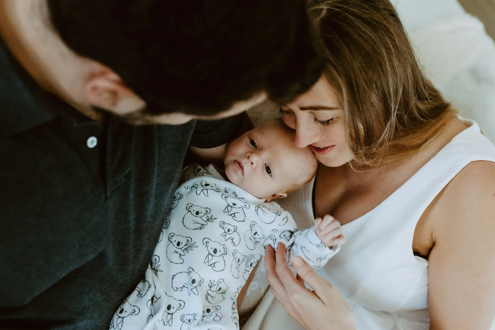 New parents kissing over their newborn son at home