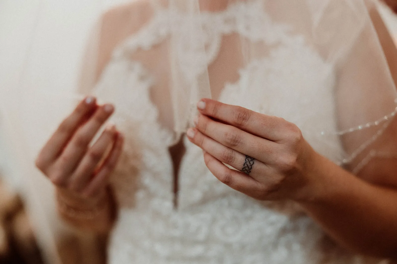 Bride's hands holding the beaded edge of her veil