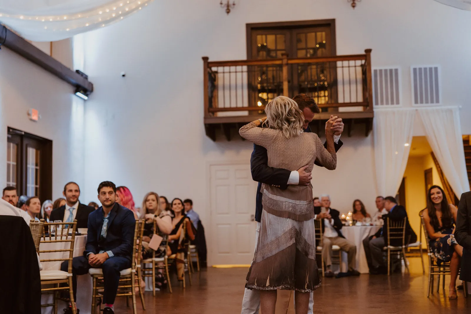 Groom dancing with a woman in a fringed dress as guests watch