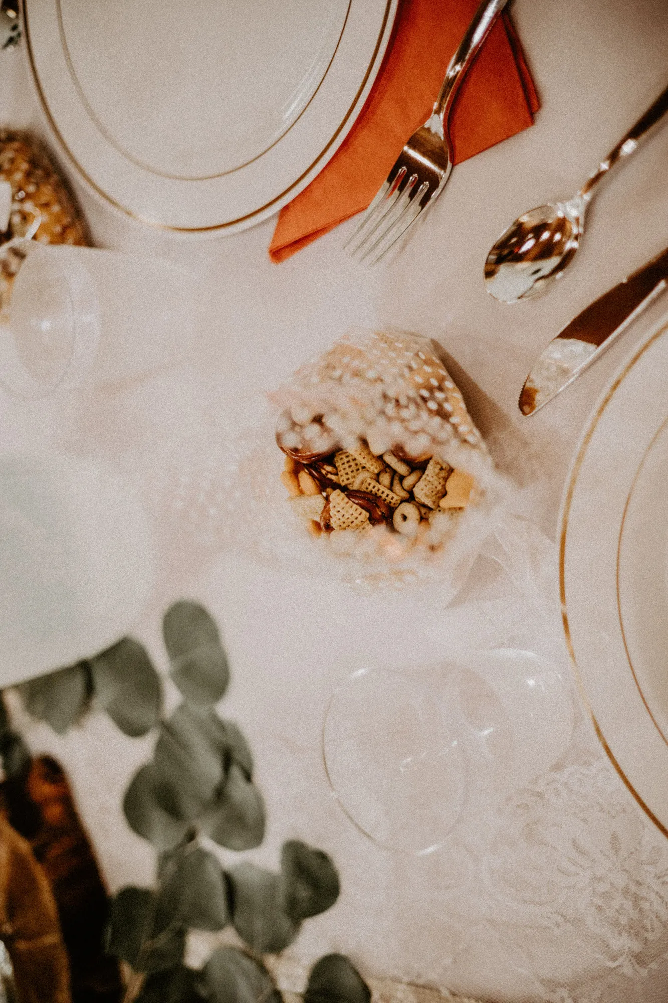 Place setting with a coral napkin and a bag of snack mix, seen from above