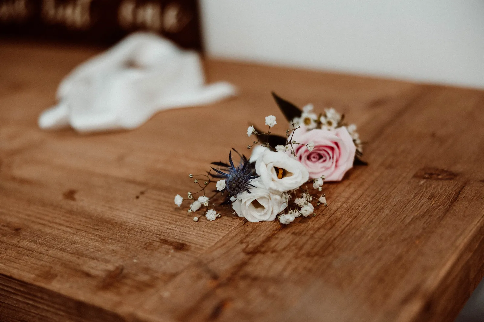 Boutonniere of pink and white flowers with thistle on a wooden table