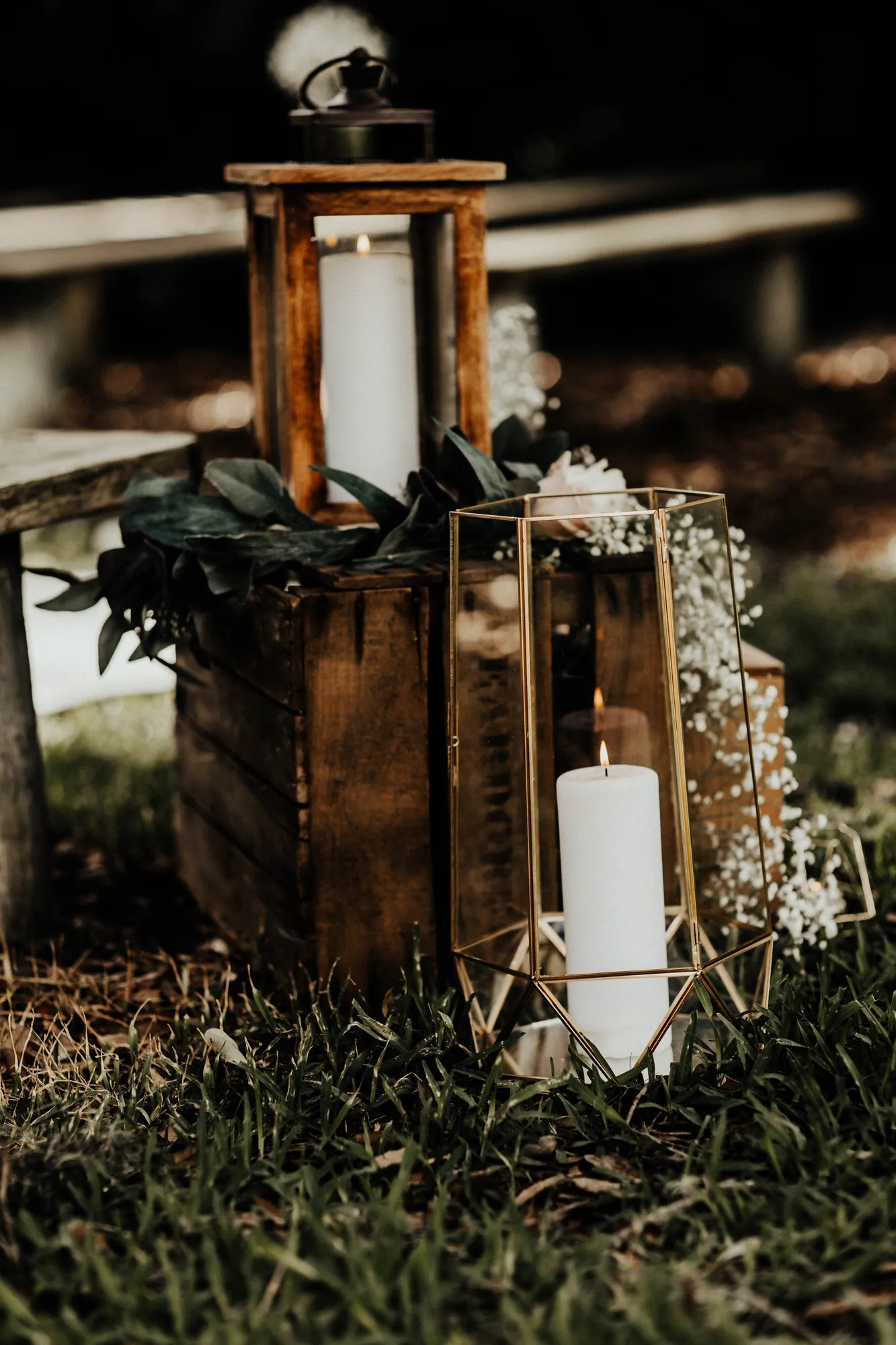 Candles in lanterns on a wooden crate beside the aisle