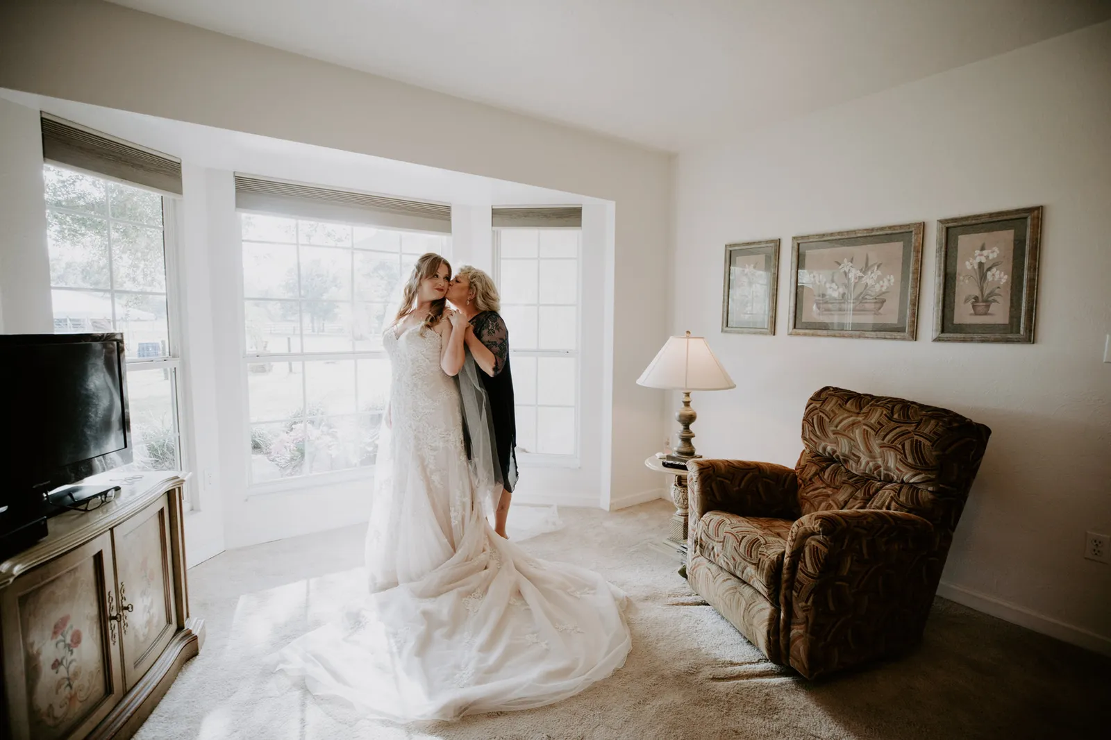 Bride hugging a woman in the living room, her train spread across the floor