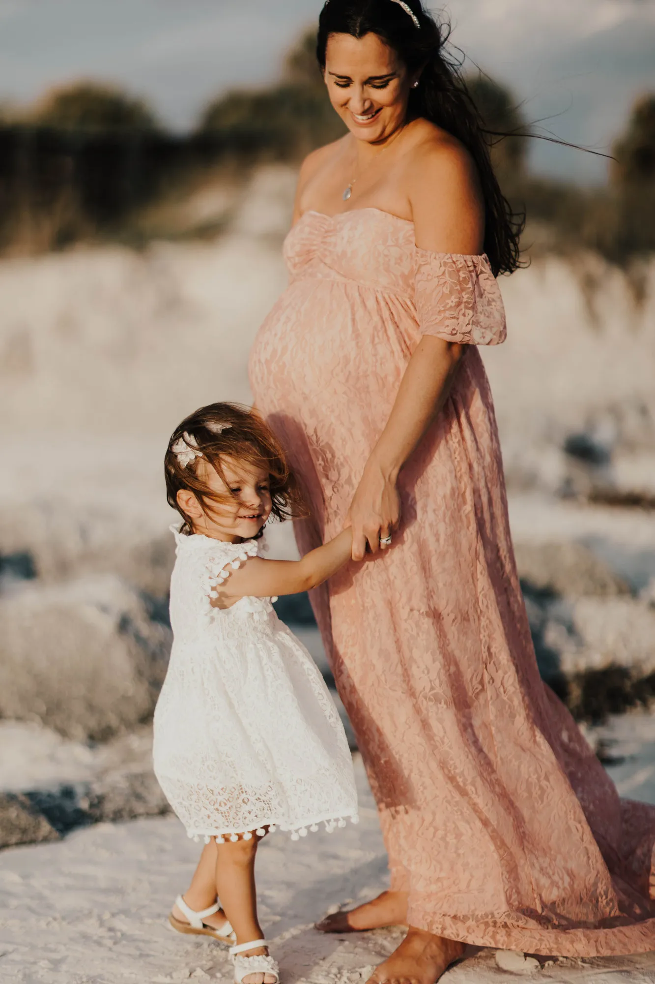 Toddler leaning against her mother's bump with her eyes closed