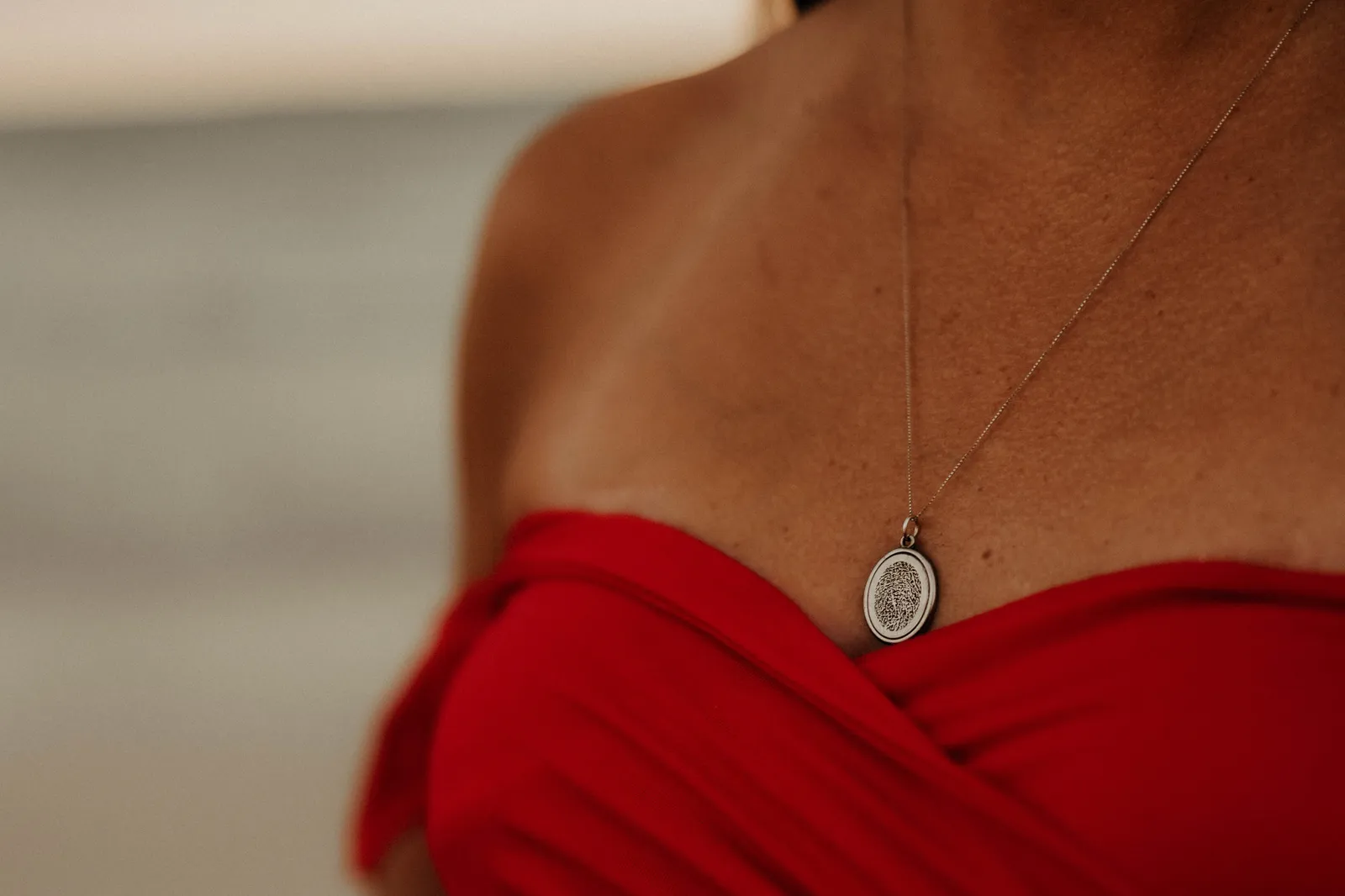 Oval pendant necklace above the neckline of a red gown