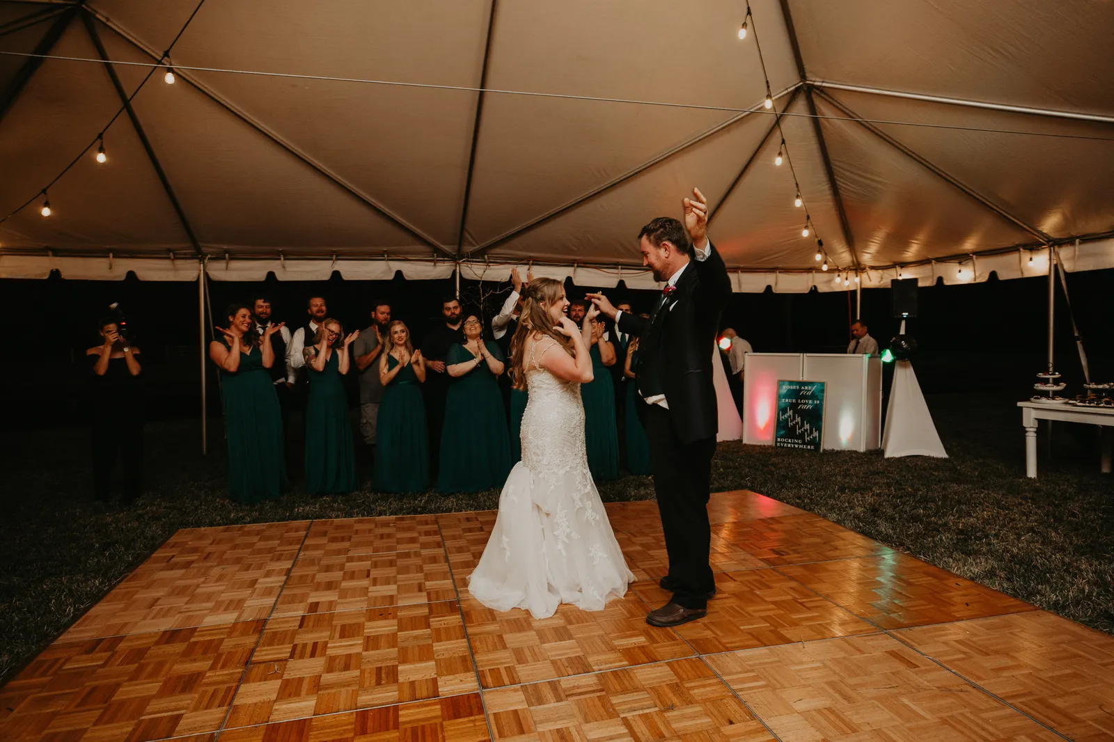 First dance on a parquet floor under a tent, the groom raising his arm