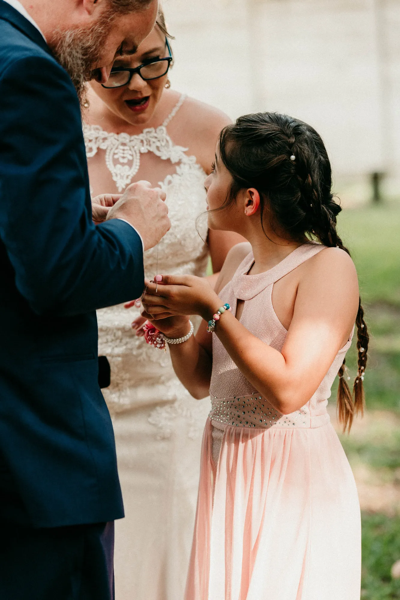 Bride and groom leaning over the girl's outstretched hands during the ceremony