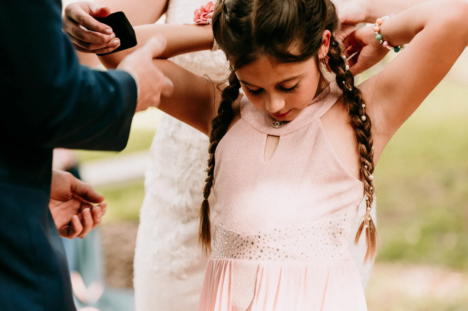 Girl looking down at a necklace as it is fastened behind her neck